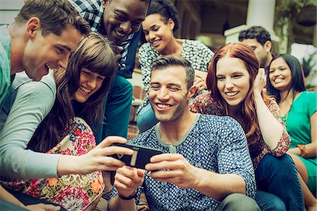A group of friends on the steps of a house porch, looking at a smart phone selfy on the screen. Foto de stock - Sin royalties Premium, Código: 6118-08521942
