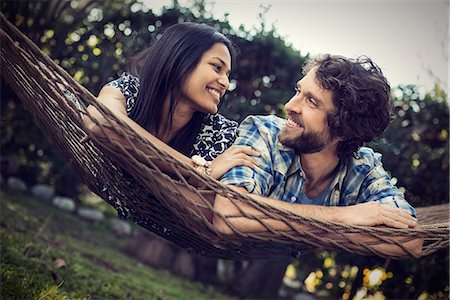 A couple, a young man and woman lying in a large hammock in the garden. Stock Photo - Premium Royalty-Free, Code: 6118-08521956