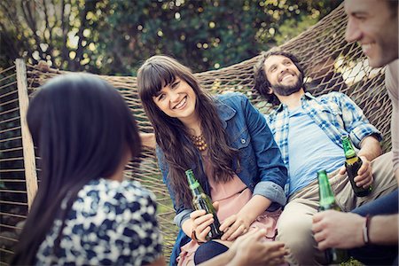 A group of friends lounging in a large hammock in the garden having a beer. Stock Photo - Premium Royalty-Free, Code: 6118-08521963