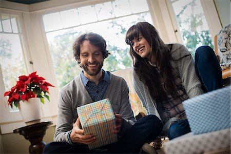 A couple on a sofa, exchanging wrapped presents. Stock Photo - Premium Royalty-Free, Code: 6118-08521908