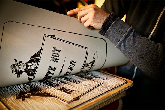 A sign writer lifting a sheet of imprinted card off a cut-out linoleum surface, a woodcut. Foto de stock - Sin royalties Premium, Código de la imagen: 6118-08659699