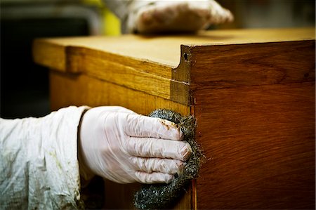 simsearch:6118-08659688,k - A person in gloves using wire wool to sand down or wax a piece of furniture. Stockbilder - Premium RF Lizenzfrei, Bildnummer: 6118-08659751