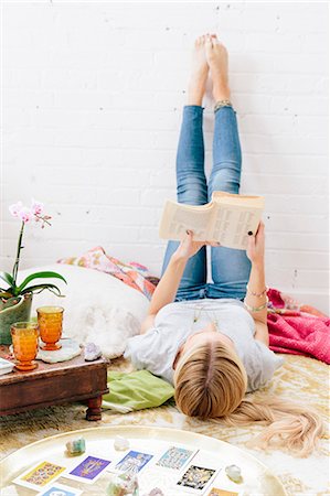 pantalón - A young woman in jeans lyng on her back with her legs against the wall. Foto de stock - Sin royalties Premium, Código: 6118-08659769