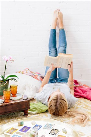 simsearch:6118-08827464,k - A young woman in jeans lyng on her back with her legs against the wall. Stockbilder - Premium RF Lizenzfrei, Bildnummer: 6118-08659769