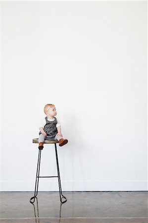 plain background - A young child, a baby girl sitting on a tall stool. Photographie de stock - Premium Libres de Droits, Code: 6118-08659712