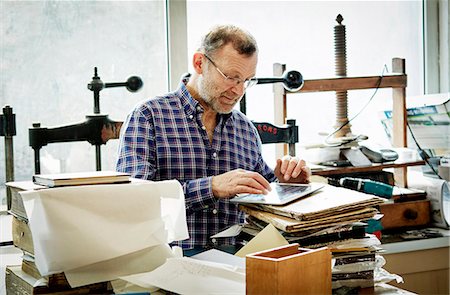A man using a digital tablet in a bookbinding workshop. Foto de stock - Sin royalties Premium, Código: 6118-08659723
