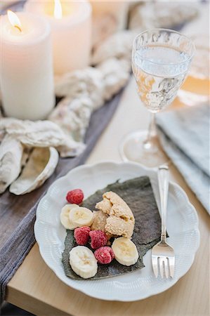 simsearch:6118-08659835,k - A table for a celebration meal with wine glasses filled and plates of fruit, and lit candles in the centre of the table. Foto de stock - Sin royalties Premium, Código: 6118-08659841