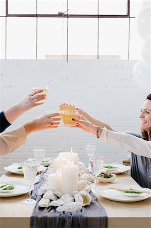 Four people raising their glasses in a toast at a meal. Stock Photo - Premium Royalty-Free, Code: 6118-08659833