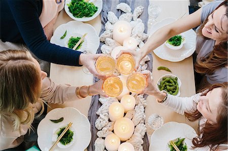 simsearch:6118-08659835,k - Overhead view of four people sharing a meal, plates of sushi and a table setting for a celebration meal. Foto de stock - Sin royalties Premium, Código: 6118-08659837