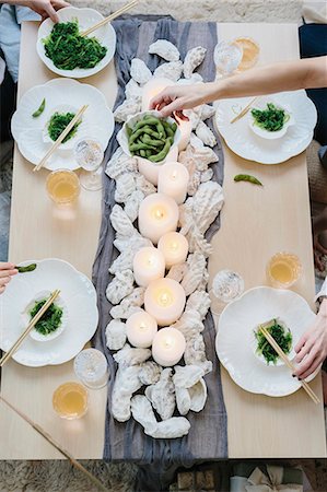 simsearch:6118-08659835,k - Overhead view of four people sharing a meal, plates of sushi and a table setting for a celebration meal. Foto de stock - Sin royalties Premium, Código: 6118-08659834