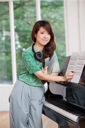 estudio de grabación - Young woman standing next to a grand piano in a rehearsal studio, holding sheet music. Foto de stock - Sin royalties Premium, Código: 6118-08659959