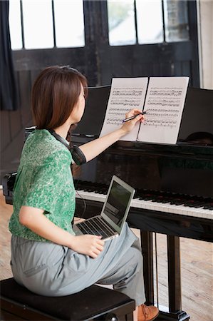 digital native - Young woman sitting at a grand piano in a rehearsal studio, annotating sheet music. Stock Photo - Premium Royalty-Free, Code: 6118-08659960