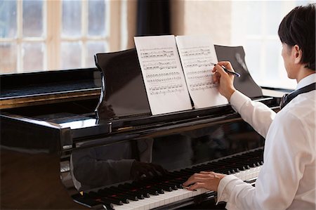 simsearch:6118-08659940,k - Young man sitting at a grand piano in a rehearsal studio, annotating sheet music. Photographie de stock - Premium Libres de Droits, Code: 6118-08659964