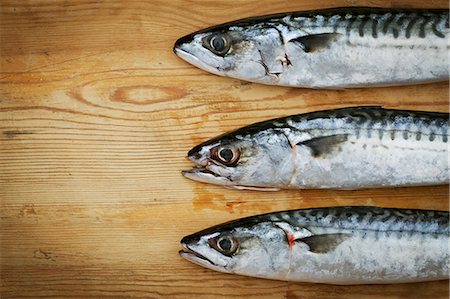 row fish - Close up of three fresh Mackerel lying on a chopping board. Stock Photo - Premium Royalty-Free, Code: 6118-08660042