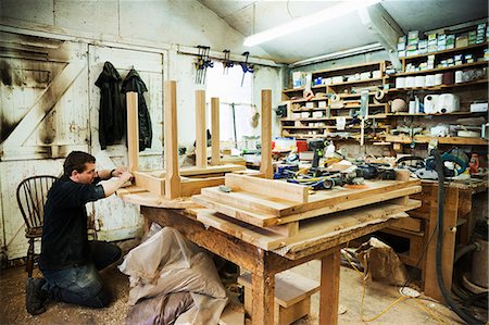 simsearch:6118-08660112,k - Man standing in a carpentry workshop, working on the skirting of a wooden table. Foto de stock - Royalty Free Premium, Número: 6118-08660082