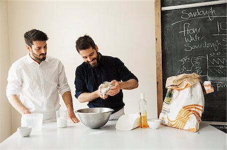 simsearch:6118-08660017,k - Two bakers standing at a table, preparing bread dough, baking ingredients and a blackboard on the wall. Stock Photo - Premium Royalty-Free, Code: 6118-08660012