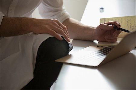 small business not mature not senior not child not teenager - Close up of a man working on a laptop computer. Stock Photo - Premium Royalty-Free, Code: 6118-08660033