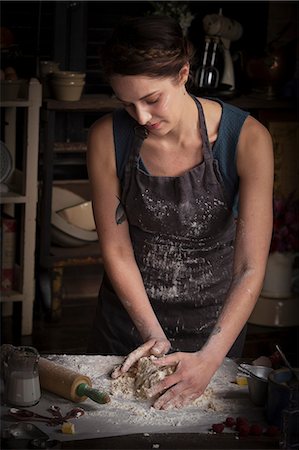 food skills - Valentine's Day baking, woman standing in a kitchen, preparing dough for biscuits. Stock Photo - Premium Royalty-Free, Code: 6118-08660169