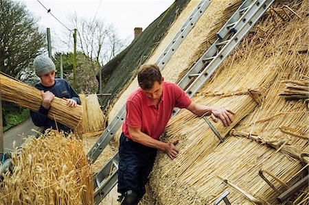 Two men thatching a roof, layering yelms of straw. Foto de stock - Sin royalties Premium, Código: 6118-08660192