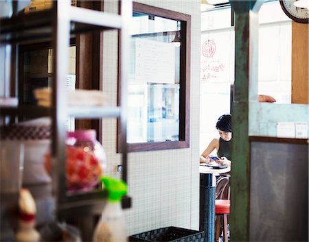 fast food city - The ramen noodle shop. A woman sitting in a cafe, view through a door. Stock Photo - Premium Royalty-Free, Code: 6118-08761691
