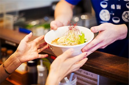 fast food city - The ramen noodle shop. A chef offering a white bowl of ramen noodle broth to a customer Stock Photo - Premium Royalty-Free, Code: 6118-08761707