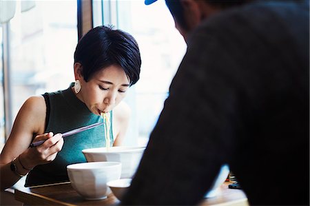 fast food city - A ramen noodle cafe in a city.  A man and woman seated eating noodles from large white bowls. Stock Photo - Premium Royalty-Free, Code: 6118-08761708