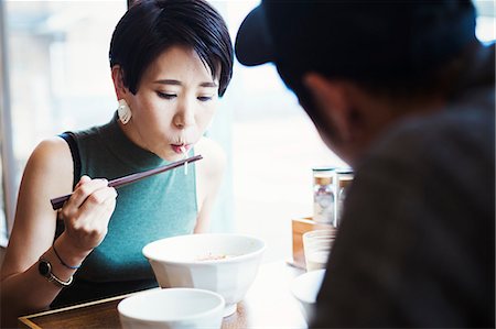 simsearch:6118-08762017,k - A ramen noodle cafe in a city.  A man and woman seated eating noodles from large white bowls. Photographie de stock - Premium Libres de Droits, Code: 6118-08761709