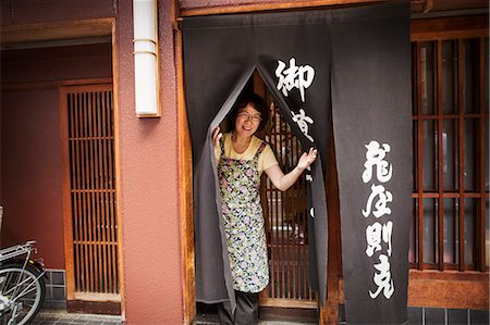 schürze - A small artisan producer of specialist treats, sweets called wagashi. A woman at the doorway of the shop. Stockbilder - Premium RF Lizenzfrei, Bildnummer: 6118-08761855
