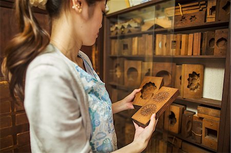 A small artisan producer of specialist treats, sweets called wagashi. A woman holding shaped wooden moulds used in the production of sweets. Stock Photo - Premium Royalty-Free, Code: 6118-08761864