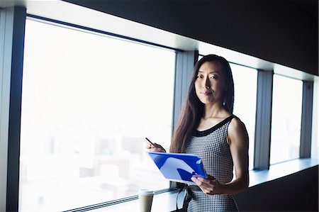 simsearch:6118-08762190,k - A business woman by a window with a view over the city, Foto de stock - Royalty Free Premium, Número: 6118-08761804