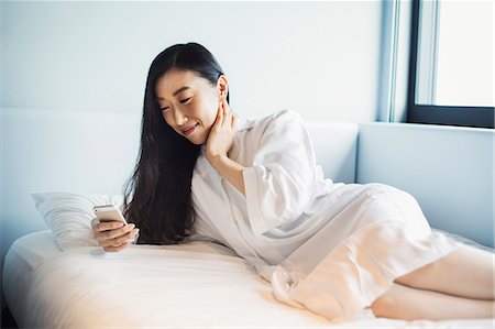 A business woman preparing for work, waking up and checking her smart phone in bed. Foto de stock - Sin royalties Premium, Código: 6118-08761824