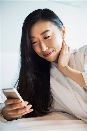 simsearch:6118-08762190,k - A business woman preparing for work, sitting in bed using her smart phone. Foto de stock - Royalty Free Premium, Número: 6118-08761825