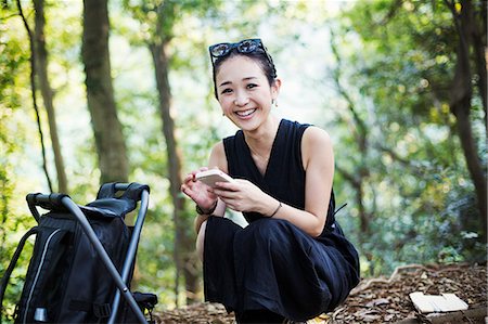 simsearch:6118-08762190,k - Smiling young woman sitting in a forest. Foto de stock - Royalty Free Premium, Número: 6118-08761956