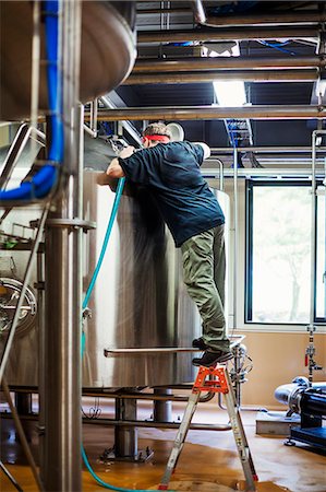 simsearch:6118-08761911,k - Man working in a brewery adjusting and checking the machinery which transfers the brewed beer around the processing plant. Foto de stock - Sin royalties Premium, Código: 6118-08761931