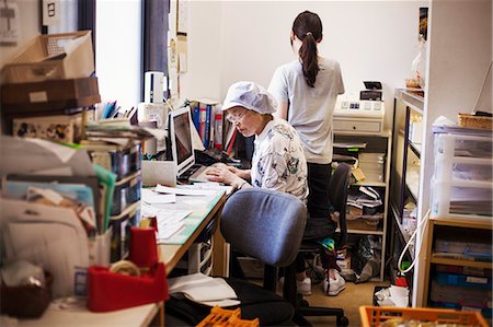 A mature woman at a desk in the office of a fast food unit and noodle production factory. Photographie de stock - Premium Libres de Droits, Code: 6118-08762016