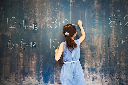 simsearch:6118-09079486,k - A group of children in school. A girl writing in chalk on a chalkboard. Foto de stock - Royalty Free Premium, Número: 6118-08762167