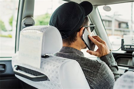 simsearch:6118-08762190,k - A man seated in the passenger seat of a car using his smart phone. Foto de stock - Royalty Free Premium, Número: 6118-08762188