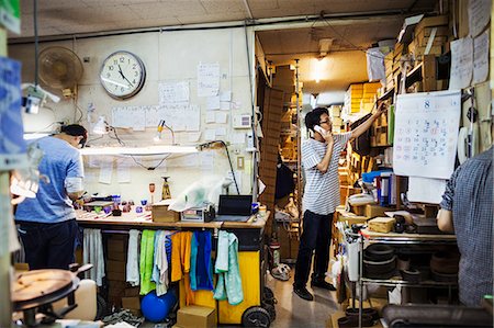 Two people at work in a glass maker's workshop and office, one on the phone. Photographie de stock - Premium Libres de Droits, Code: 6118-08762103