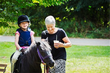 persona mayor (hombre y mujer) - Woman and blond girl wearing riding hat sitting on a pony. Foto de stock - Sin royalties Premium, Código: 6118-08797516