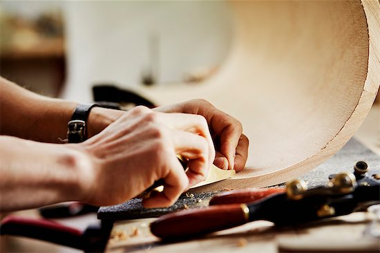 A furniture workshop making bespoke contemporary furniture pieces using traditional skills in modern design. A man working on a piece of curved wood. Stock Photo - Premium Royalty-Free, Image code: 6118-08725443