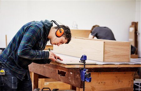simsearch:6118-08660112,k - A furniture workshop making bespoke contemporary furniture pieces using traditional skills in modern design. A man marking a piece of wood with a pencil. Foto de stock - Royalty Free Premium, Número: 6118-08725449