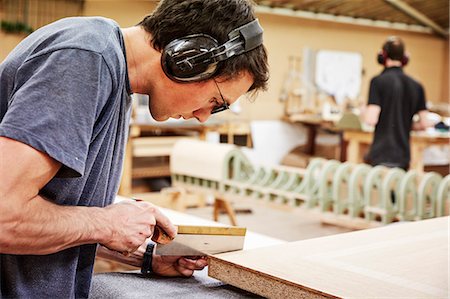 A furniture workshop making bespoke contemporary furniture pieces using traditional skills in modern design. A man using a small handsaw to trim wood. Stock Photo - Premium Royalty-Free, Code: 6118-08725451