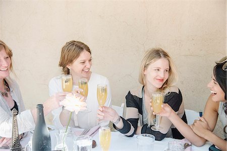 simsearch:649-09278006,k - Four smiling women sitting at a table, holding glasses of champagne, toasting. Stock Photo - Premium Royalty-Free, Code: 6118-08725554