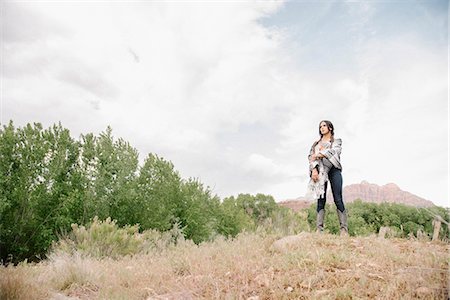 simsearch:6118-07731806,k - Young woman with long brown hair standing in a prairie under a cloudy sky. Photographie de stock - Premium Libres de Droits, Code: 6118-08725565