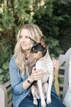 dog usa - Blond woman sitting on a bench in a garden, a dog on her lap. Stock Photo - Premium Royalty-Free, Code: 6118-08725517