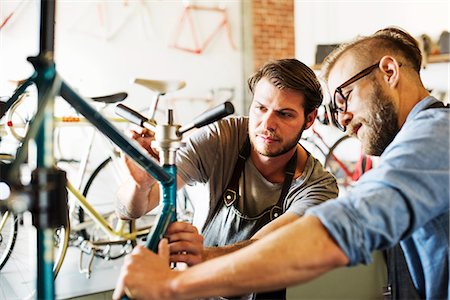 simsearch:6118-08725675,k - Two men in a cycle repair shop, looking at a bicycle. Stock Photo - Premium Royalty-Free, Code: 6118-08725663