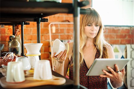 Woman in a shop, holding a digital tablet and small ceramic pot. Photographie de stock - Premium Libres de Droits, Code: 6118-08725711