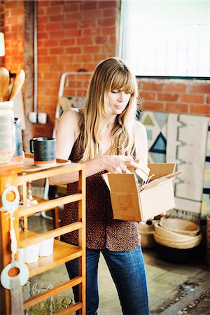 supermarket business cards - Woman in a shop, holding a small cardboard box with merchandise. Stock Photo - Premium Royalty-Free, Code: 6118-08725715