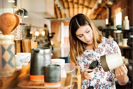 selling entrepreneur pictures - Young woman in a shop, scanning the barcode of a ceramic jug with a barcode scanner. Stock Photo - Premium Royalty-Free, Code: 6118-08725718