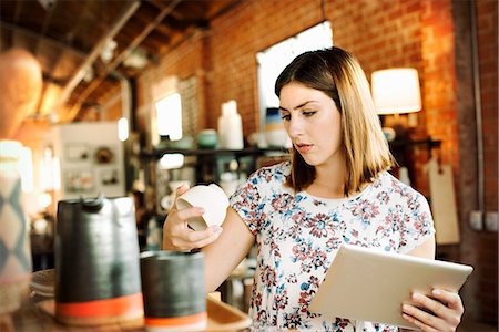 Young woman in a shop, holding a digital tablet and a ceramic mug. Foto de stock - Sin royalties Premium, Código: 6118-08725720